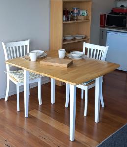 une table en bois avec quatre chaises et une cuisine dans l'établissement Addictive View - Lakeside Studio, à Rotorua