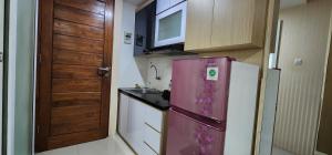 eine Küche mit einem rosa Kühlschrank und einer Spüle in der Unterkunft Apartemen Green Park Yogyakarta in Seturan