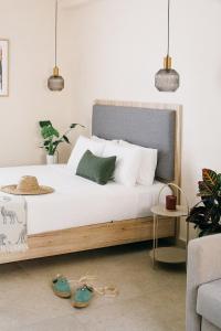 - une chambre avec un lit doté de draps blancs et d'oreillers verts dans l'établissement Limeria studios & maisonettes, à Parga