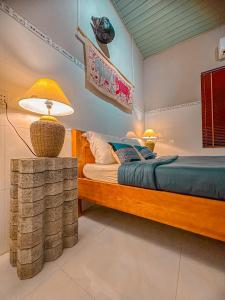um quarto com uma cama e um candeeiro sobre uma mesa em Chang's Hideaway homestay ConDao em Con Dao