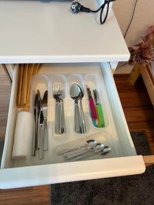 a drawer filled with utensils in a white cabinet at Apartment (2) am Stuttgarter Flughafen / Messe in Leinfelden-Echterdingen