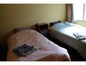 1 dormitorio con 2 camas y una bolsa en la cama en Asahikawa Henshushitsu - Vacation STAY 13647, en Asahikawa