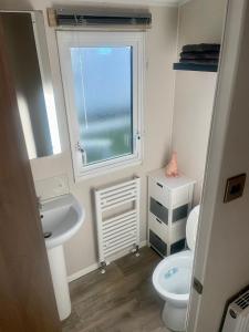 łazienka z umywalką, toaletą i oknem w obiekcie Charming 2-Bed Chalet in Tuxford w mieście Tuxford