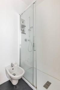 een witte badkamer met een douche en een wastafel bij Antoniana in La Spezia