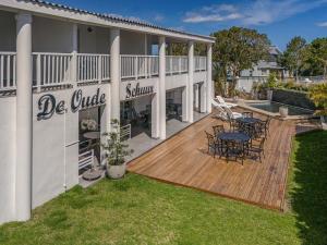 a deck with chairs and tables on a house at Oude Schuur Boutique Guesthouse in Hermanus