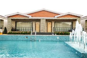 a house with a swimming pool with a fountain at Grand Beach Resort in Mandarmoni