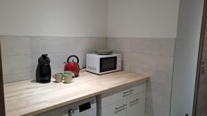 a kitchen counter with a microwave and some mugs at Chez Grégory et Nadine in Houssen