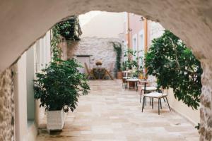 an arched doorway to a courtyard with tables and chairs at Limeria studios & maisonettes in Parga