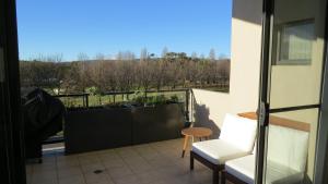 d'un balcon avec une table et une chaise offrant une vue. dans l'établissement GREENWAY WATERS Apartments, à Tuggeranong