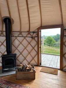 a room with a stove and a door to a porch at Bracken Yurt at Walnut Farm Glamping in Netherbury