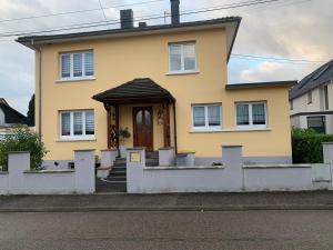 une maison jaune avec une terrasse couverte et une porte dans l'établissement Appartement neuf 1 à 6 personnes dans maison individuelle, à Haguenau