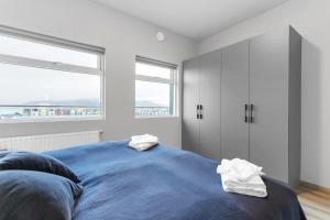 ein Schlafzimmer mit einem blauen Bett mit zwei Handtüchern darauf in der Unterkunft Downtown City Gem! in Reykjavík