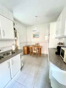 eine Küche mit weißen Schränken und einem Tisch darin in der Unterkunft CASA EN PLENO CENTRO DE LA CALA DE MIJAS by Holidays2Rent in La Cala de Mijas