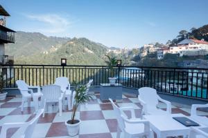 a patio with white chairs and tables on a balcony at PerfectStayz Mall Road Mussoorie in Mussoorie