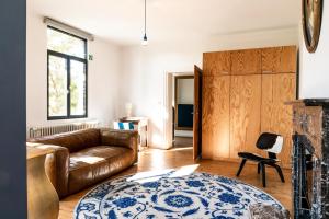 a living room with a leather couch and a fireplace at Hullehuis in Lotenhulle