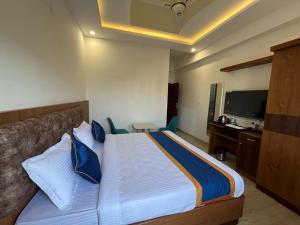 a bedroom with a bed and a desk and a television at NP Royal INN in Bangalore