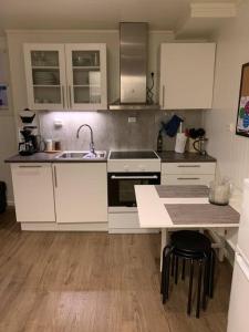 a kitchen with white cabinets and a sink and a table at Gimle cozy apartment in Tromsø
