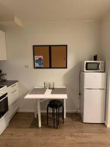 a small kitchen with a white table and a microwave at Gimle cozy apartment in Tromsø