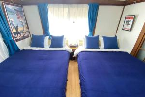 2 camas en una habitación con cortinas azules y ventana en Good aces to Shibuya/2mins walk sta/Max12ppl/1flor en Tokio