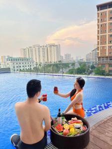 Ein Mann und eine Frau sitzen mit einem Tablett Essen im Wasser. in der Unterkunft Serviced apartment with pool- Greenpearl Bắc Ninh in Hòa Ðình