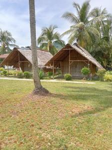 two houses with palm trees in a field at koh mook oyoy reggaebar bungalow in Koh Mook