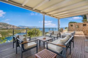 una terraza con sillas y mesas y vistas al agua en Alfresco Villas, en Sivota