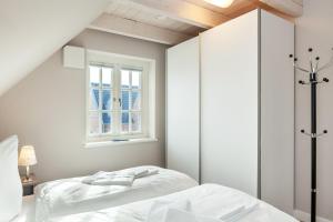 een witte slaapkamer met een bed en een raam bij Moin Moin in List