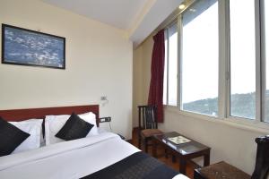 a bedroom with a bed and a large window at Hotel M Bar and Restaurant in McLeod Ganj