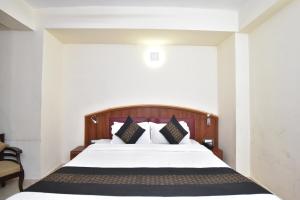 a bedroom with a bed with white sheets and pillows at Hotel M Bar and Restaurant in McLeod Ganj
