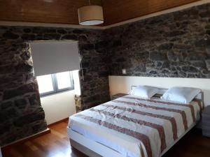a bedroom with a bed and a stone wall at Quinta Escola in Arco da Calheta