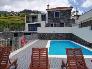 a villa with a swimming pool and two chairs at Quinta Escola in Arco da Calheta