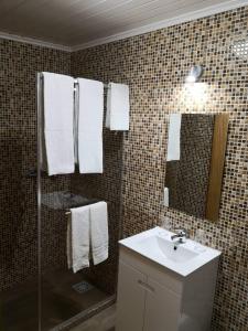 a bathroom with a sink and a shower with towels at Quinta Escola in Arco da Calheta
