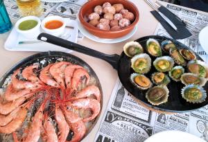 una mesa con una sartén de camarones y otros alimentos en Evita Beach Suites Exclusivas en Caleta de Sebo