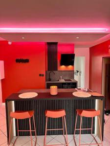 una cocina con paredes rojas y un bar con taburetes en NEW : Le Terracotta proche Metz, 
