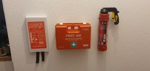 a first aid kit and a fire extinguisher hanging on a wall at FW 3 Zimmer 1OG 80qm 