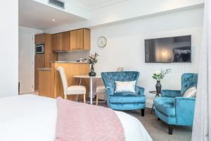 Cet appartement comprend une chambre avec un lit et deux chaises ainsi qu'une cuisine. dans l'établissement Comfortable & Cozy - Newly Furnished 'Quays' Share Save, à Auckland