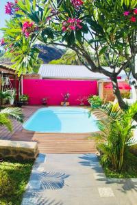 een zwembad op een houten terras met een roze muur bij Villa Terol, à proximité de l’océan in Saint-Paul