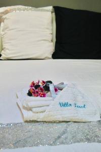 een witte handdoek met bloemen op het bed bij Villa Terol, à proximité de l’océan in Saint-Paul