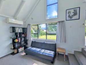 a living room with a couch and a window at Rotorua redwood retreat in Rotorua