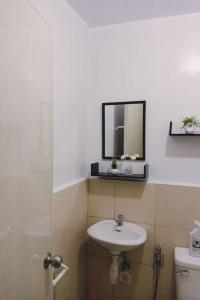 ein Badezimmer mit einem Waschbecken, einem Spiegel und einem WC in der Unterkunft Staycation in Marilao in Marilao