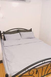 Bett mit weißer Bettwäsche und Kissen in einem Zimmer in der Unterkunft Staycation in Marilao in Marilao