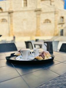 uma bandeja com chávenas de café e croissants numa mesa em B&B - Piazza Grande em Gela