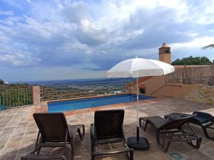 eine Terrasse mit Stühlen und Sonnenschirm und ein Pool in der Unterkunft Casa Rural El Mirador in Vélez-Málaga