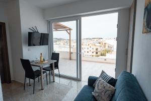 a living room with a blue couch and a table with chairs at The Willows Penthouses with Jacuzzi in Għajn il-Kbira