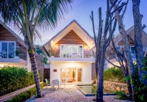 a house with palm trees in front of it at Koh Apikjun Resort in Kaoh Sdach