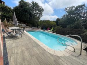 a swimming pool with a table and an umbrella at Escale Douceur d'Estérel in Saint-Raphaël