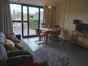 uma sala de estar com um sofá e uma mesa com cadeiras em Het Zonnetje -Vakantiewoning en Bed and Breakfast em Dilsen-Stokkem