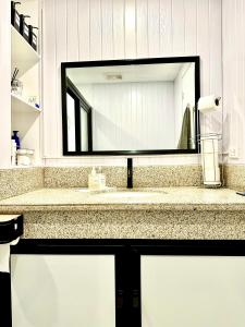 bagno con lavandino e grande specchio di YourHomeAway,LuxFlat at BristleRidge Baguio a Baguio