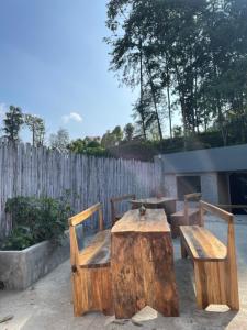 Rilassare stays cottage في Pedong: طاولة خشبية وكرسيين وطاولة وسياج