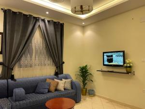 a living room with a blue couch and a tv at فخامة المصيف للشقق المخدومة 2 in Taif